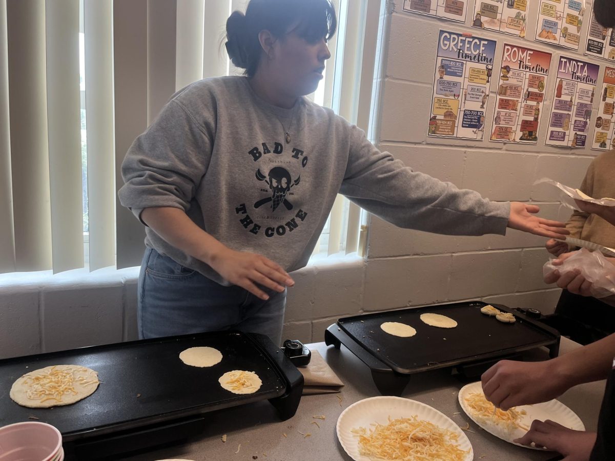 Ms. Sanchez is helping her students with making the tortillas for a tasty treat  in class!