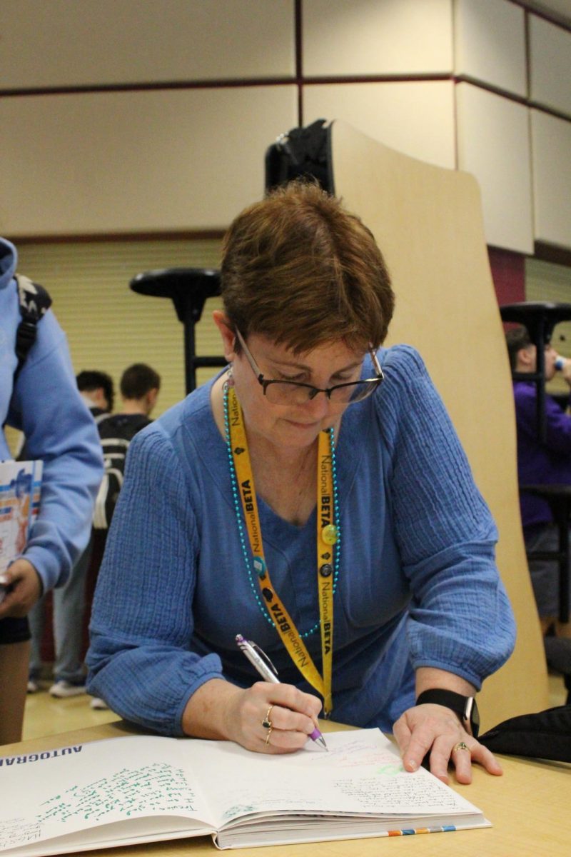 Mrs Brady signs a students yearbook.