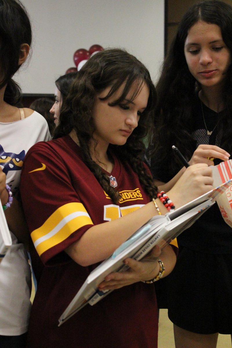 Brenna Restituto signers her friends yearbook at the 8th grade signing party.