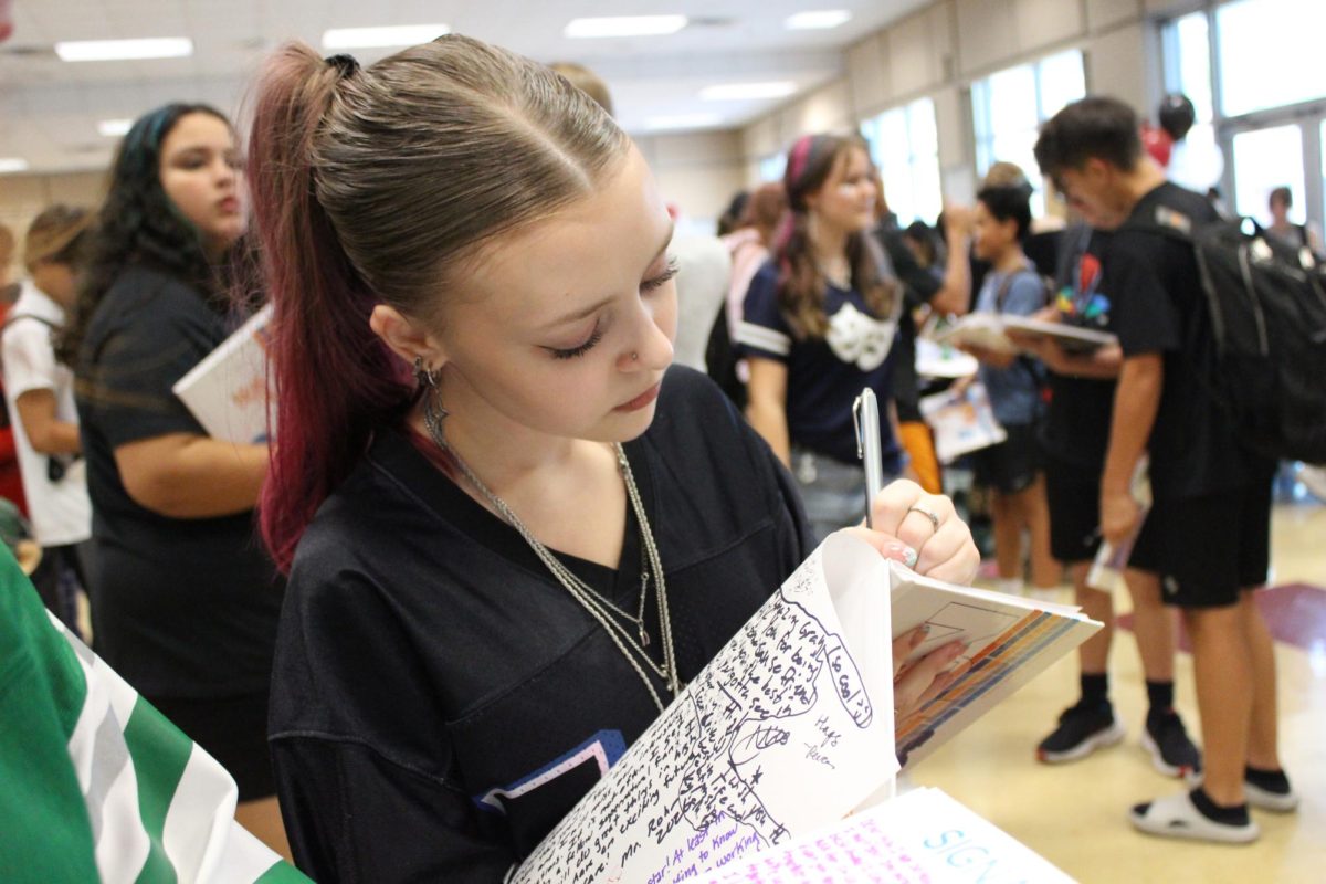 Lyla Daugherty (8) is signing her friends yearbooks and enjoying the snacks they provided at the 8th grade yearbook signing party.