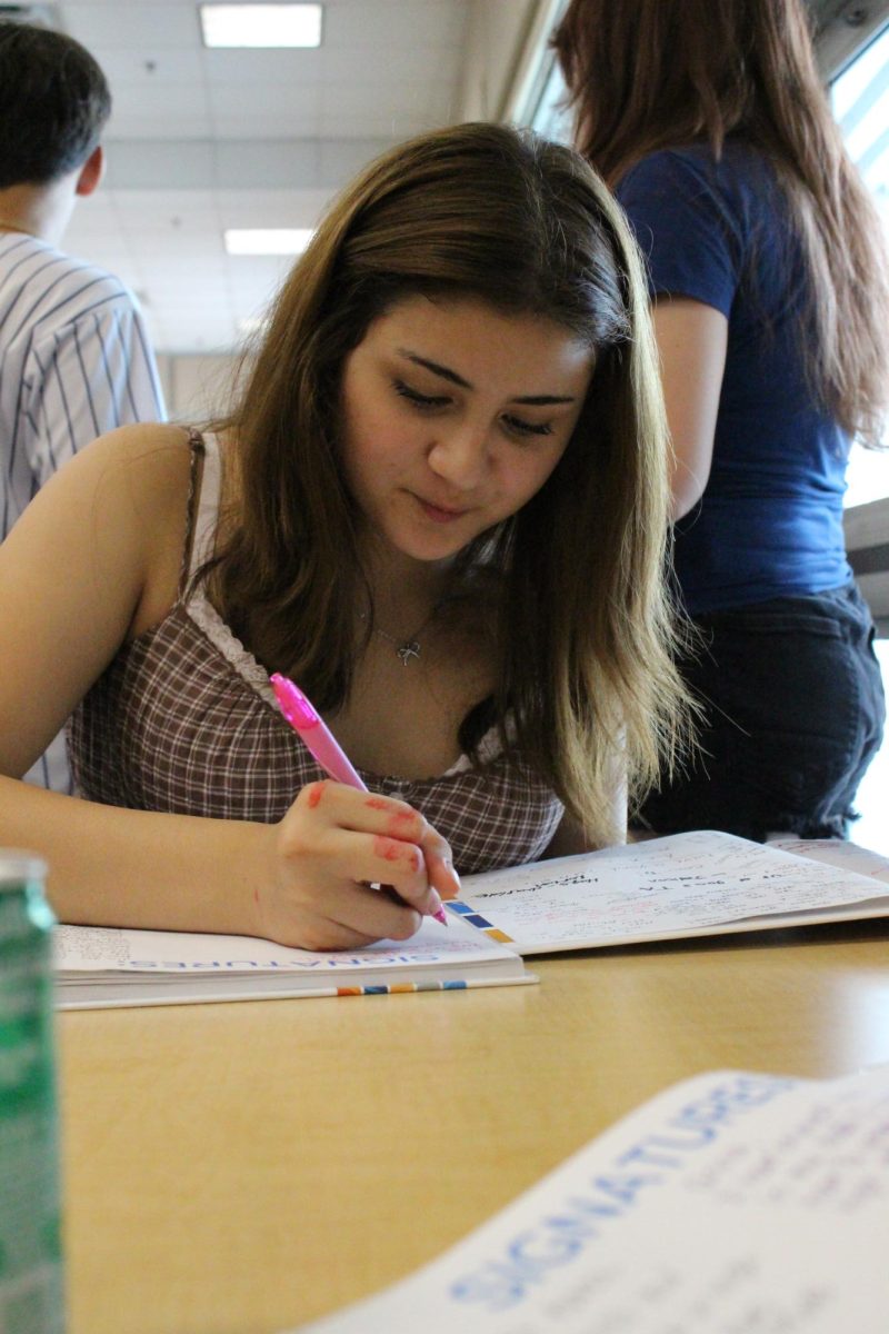 8th grade Quinn Dozier, signing a friends yearbook, before the signing party is over.